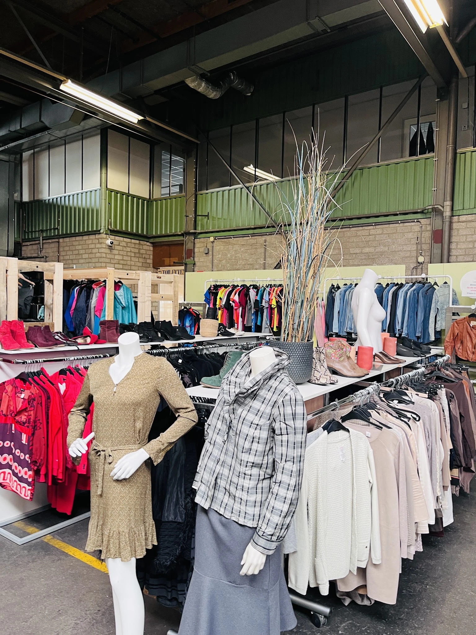 Rekken met tweedehands kleding, waaronder jassen, truien en blouses op hangers in de winkelruimte