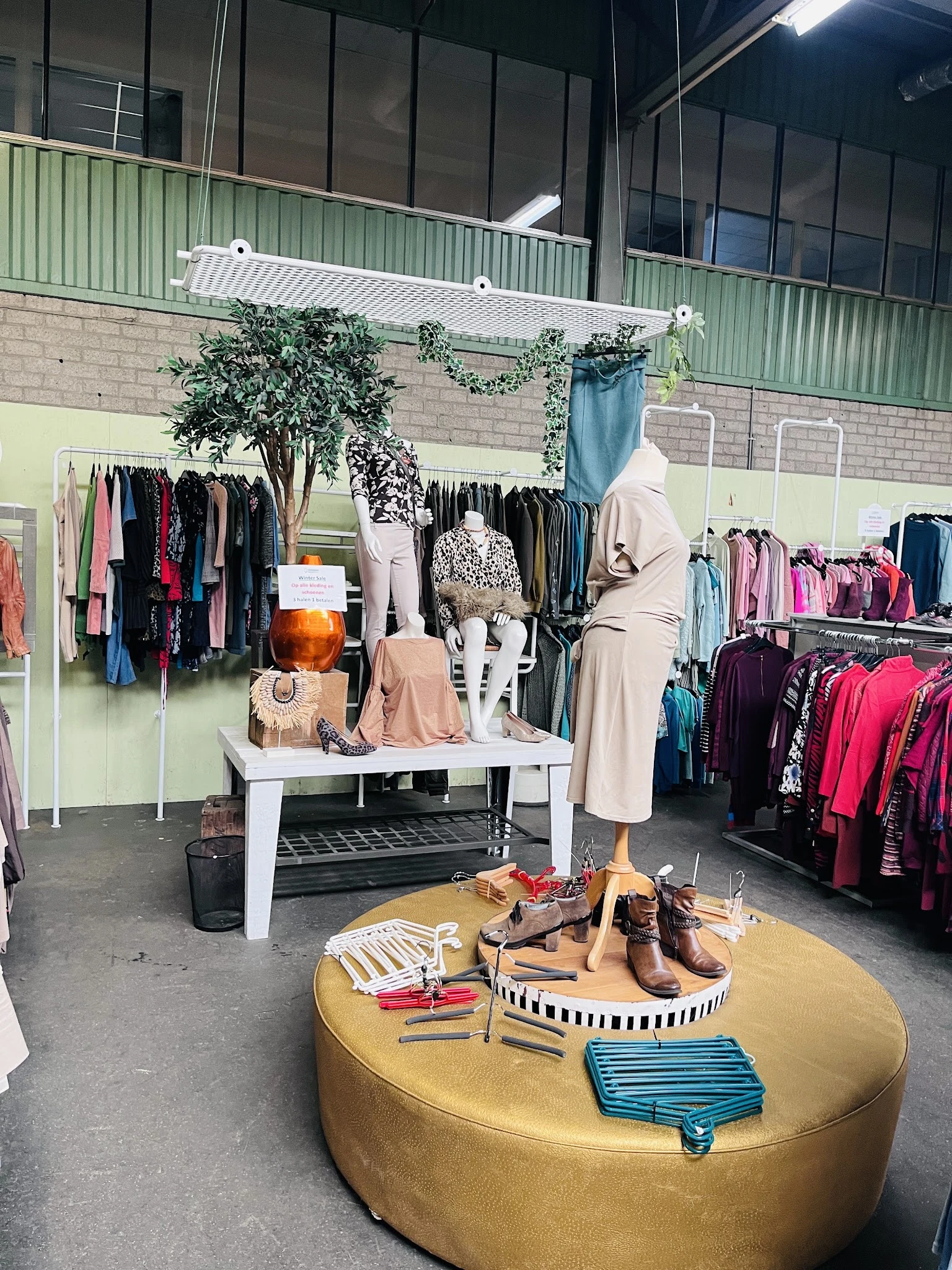 Uitgestalde tweedehands kleding en accessoires met etalagepop en schoenen in kringloopwinkel