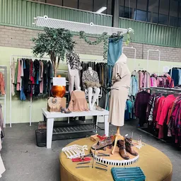 Uitgestalde tweedehands kleding en accessoires met etalagepop en schoenen in kringloopwinkel