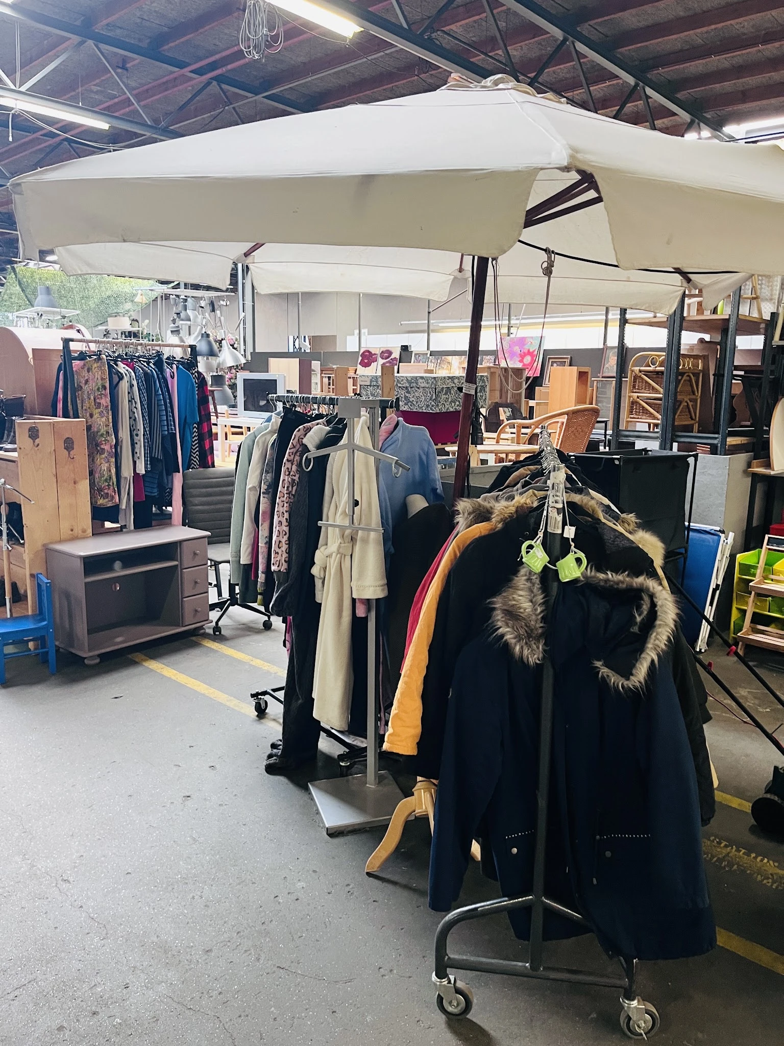 Rekken met tweedehands kleding, jassen en accessoires in de kringloopwinkel