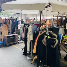 Rekken met tweedehands kleding, jassen en accessoires in de kringloopwinkel