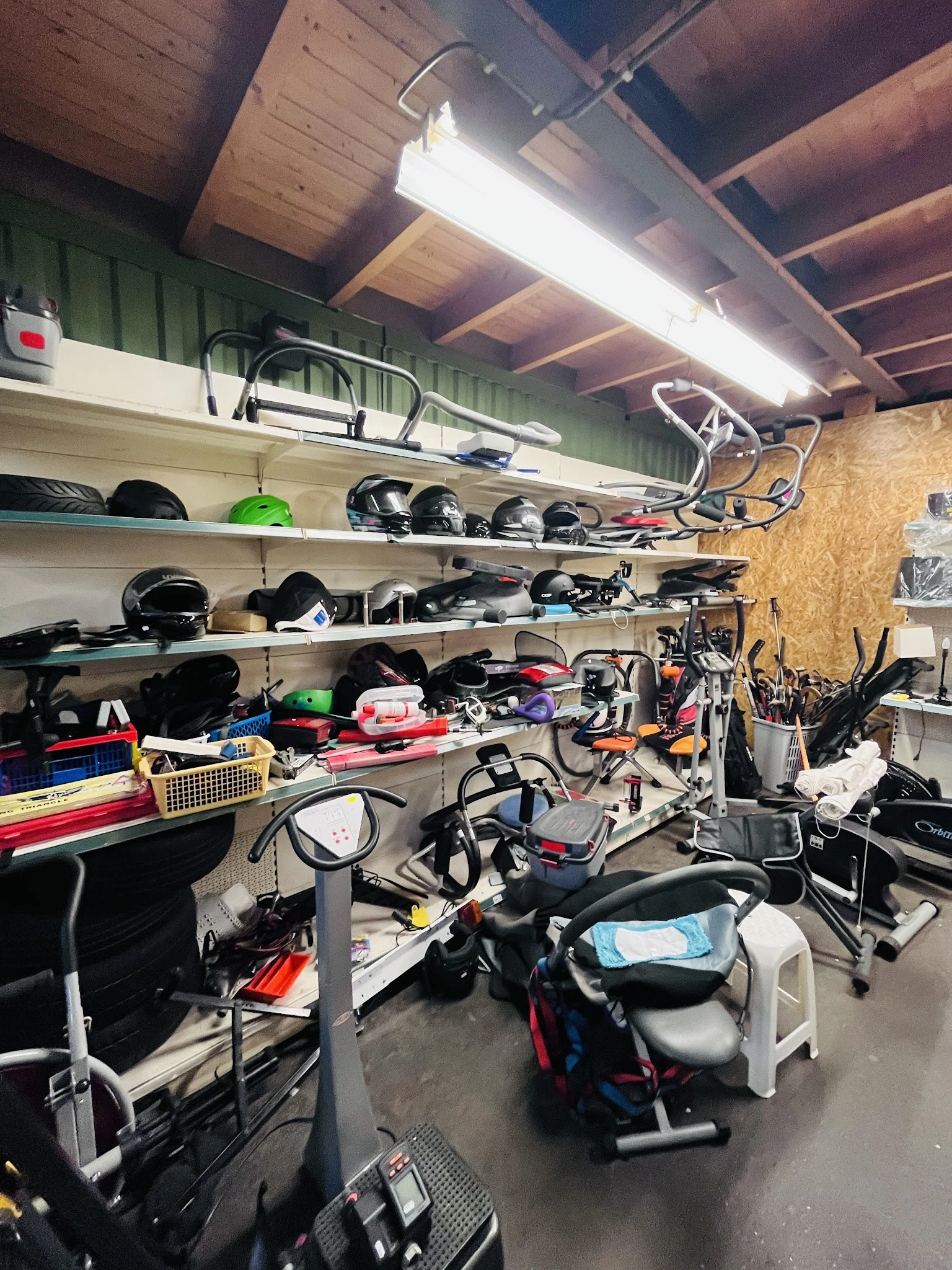 Volle stellingen met diverse tweedehands spullen, fietsen en sportmateriaal in een kringloopwinkel