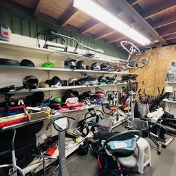 Volle stellingen met diverse tweedehands spullen, fietsen en sportmateriaal in een kringloopwinkel