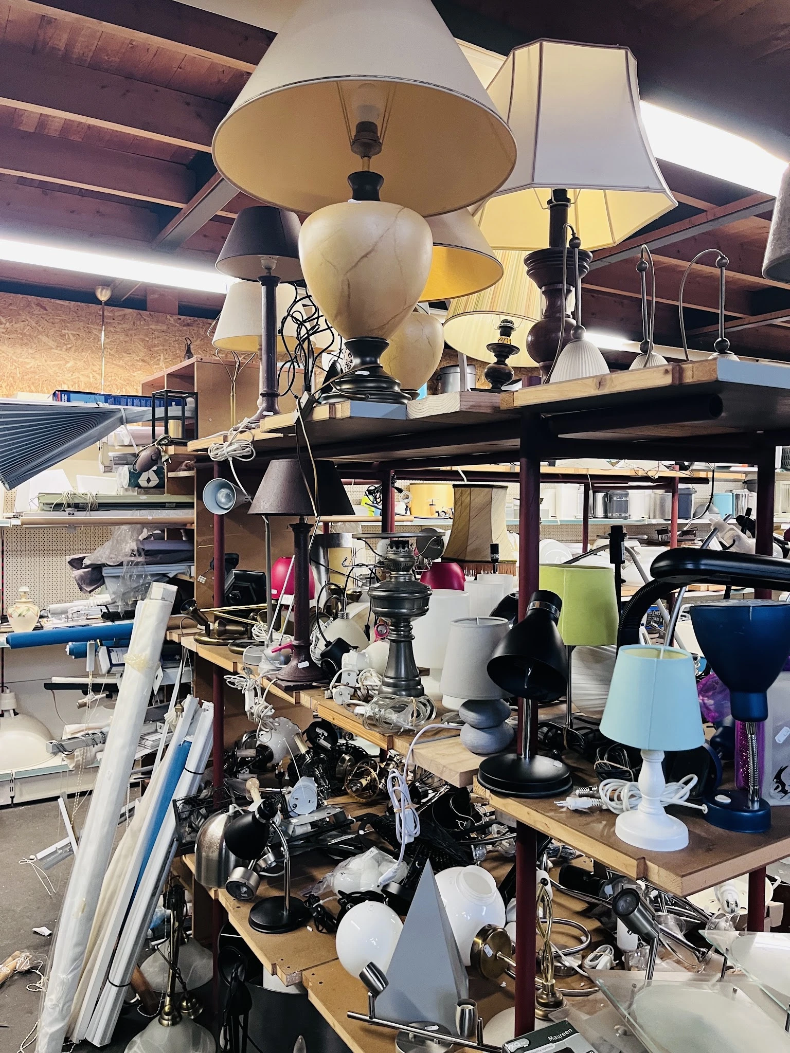 Overzicht van winkelvloer met diverse hanglampen, tafels en spullen in een kringloopwinkel