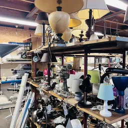 Overzicht van winkelvloer met diverse hanglampen, tafels en spullen in een kringloopwinkel