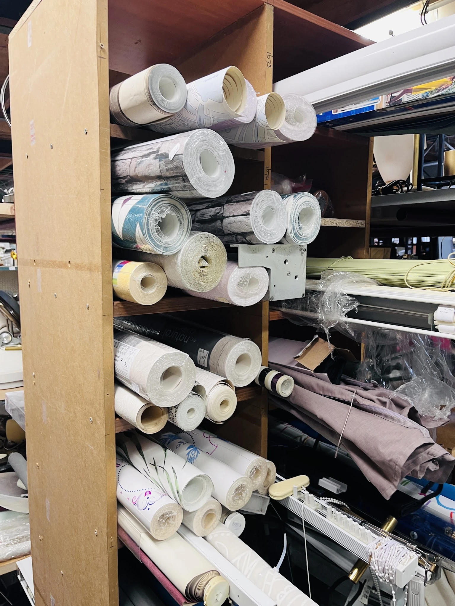 Stellingen met rollen behang en andere bouwmaterialen in de kringloopwinkel