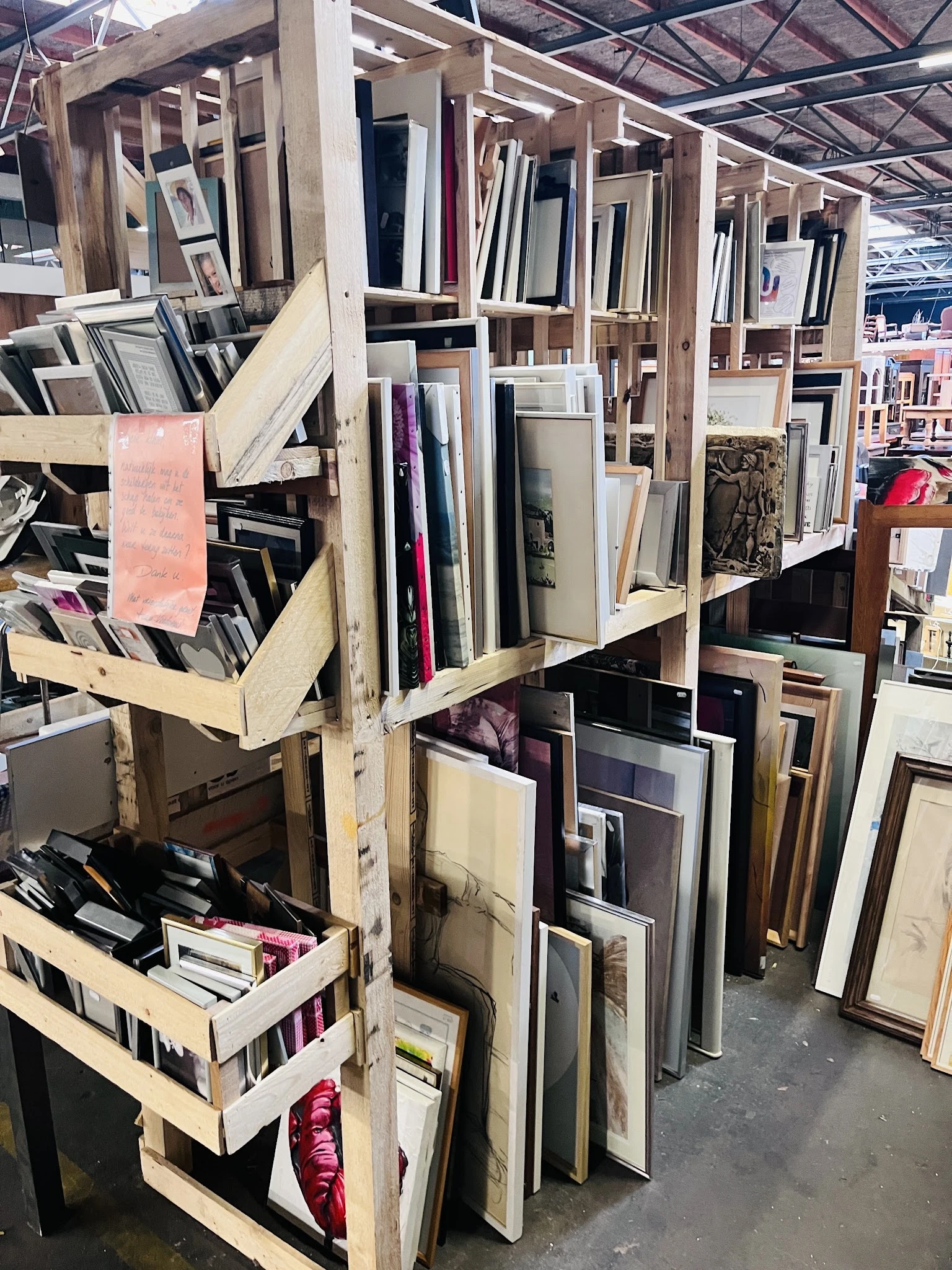 Stellingen met uiteenlopende tweedehands artikelen zoals spiegels, frames en decoratieve items