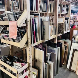 Stellingen met uiteenlopende tweedehands artikelen zoals spiegels, frames en decoratieve items