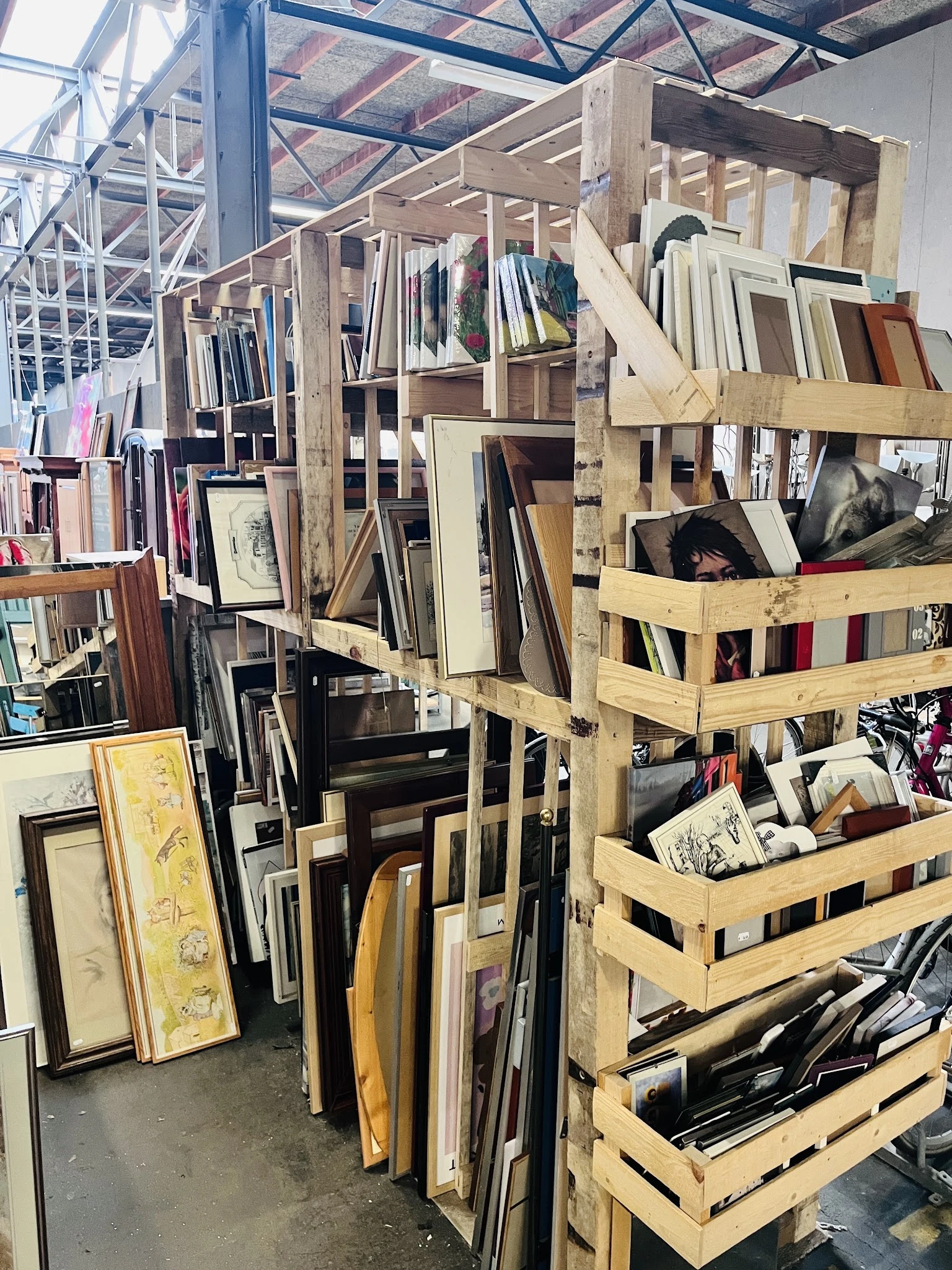 Houten rekken en stellingen vol met ingelijste prenten, schilderijen, kunstwerken en frames in verschillende formaten