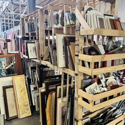 Houten rekken en stellingen vol met ingelijste prenten, schilderijen, kunstwerken en frames in verschillende formaten