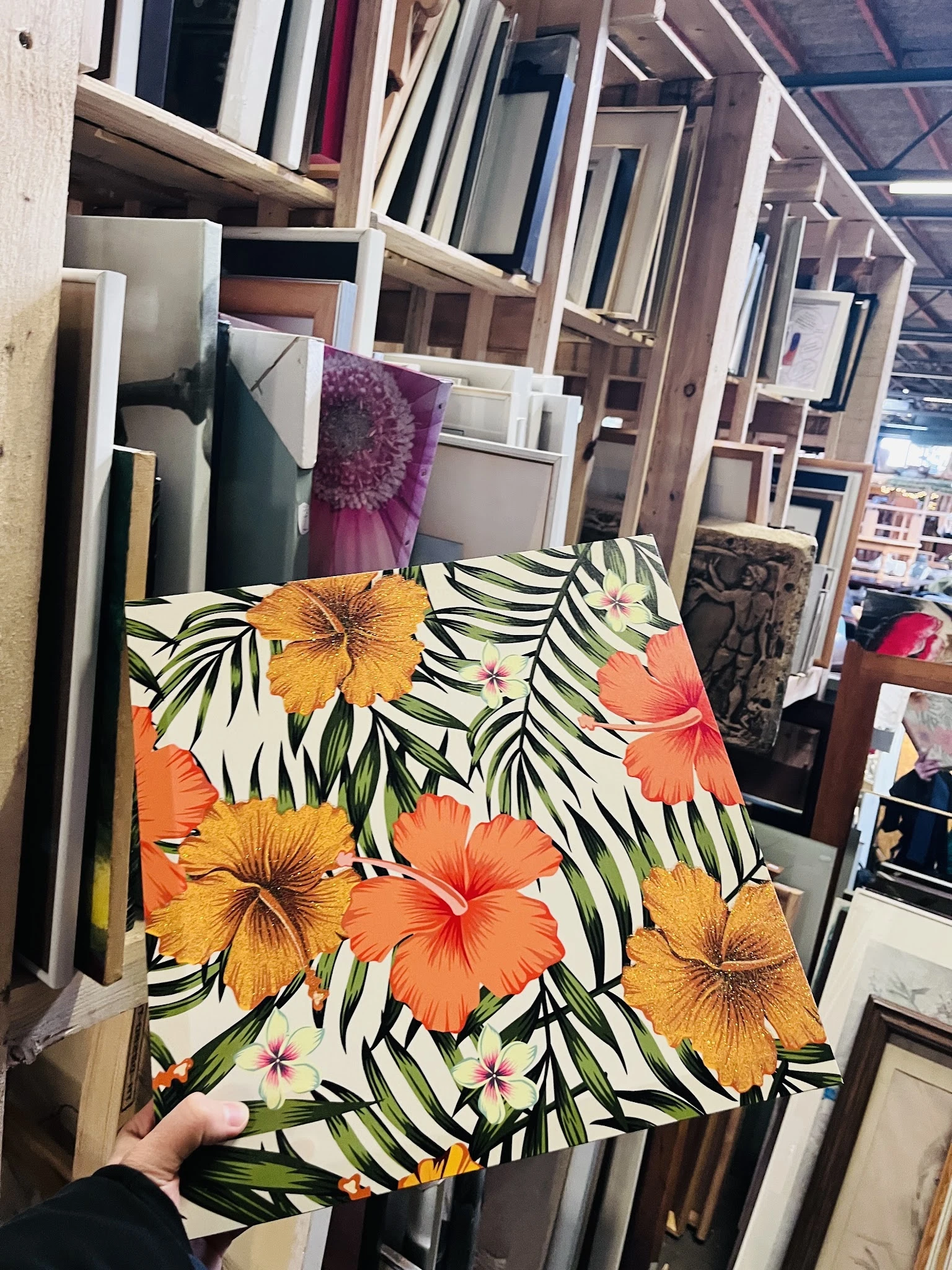 Close-up van een kussen of textiel met hibiscusbloemen in oranje en geel op zwarte bladmotief