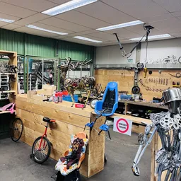 Werkplaats van fietsenreparatie met houten werkbank, gereedschapskast, hangende fietsen en reparatiemateriaal