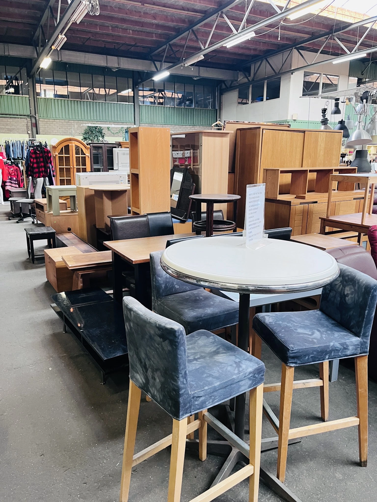 Ronde witte tafel met grijze stoelen en houten meubels op display in kringloopwinkel
