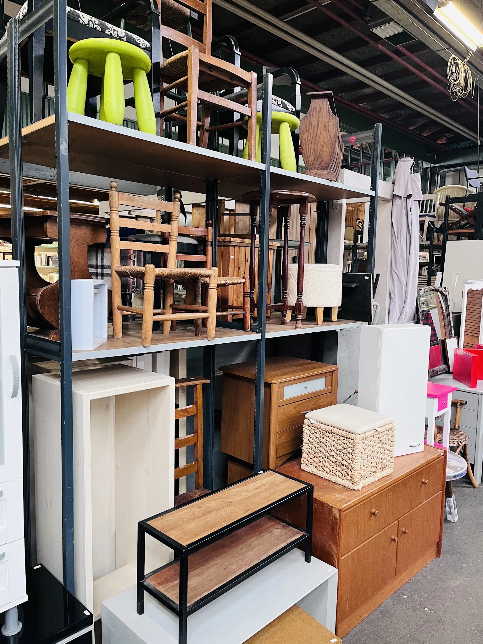 Houten meubels en huishoudartikelen op stellingen in de kringloopwinkel