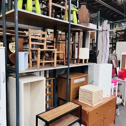 Houten meubels en huishoudartikelen op stellingen in de kringloopwinkel