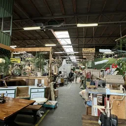 Binnenaanzicht van kringloopwinkel met stellingen, toonbanken, diverse artikelen en bezoekers op de vloer
