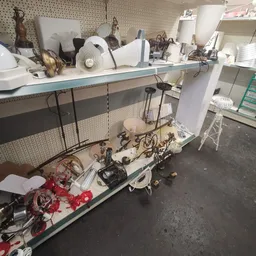 Verzameling tweedehands elektrische apparaten en onderdelen onder een werkbank in de winkel