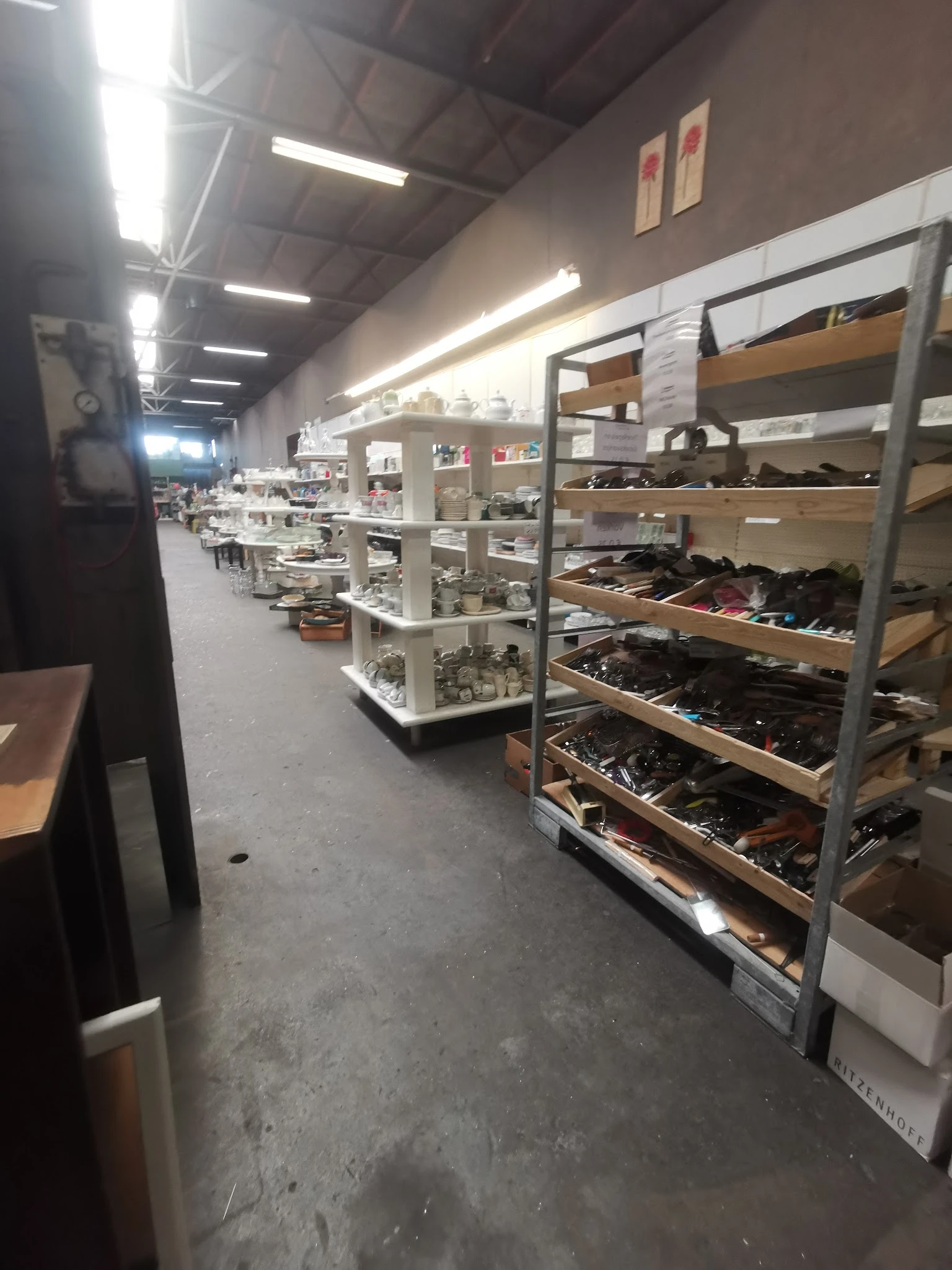 Stellingen met uitgestalde schoenen en laarzen in verschillende kleuren in een kringloopwinkel