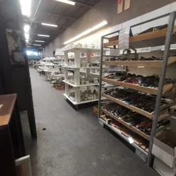 Stellingen met uitgestalde schoenen en laarzen in verschillende kleuren in een kringloopwinkel