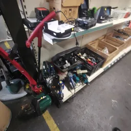 Kratten en bakken met gebruikt gereedschap en elektrische apparaten op een werktafel
