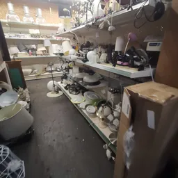 Kringloopwinkelinterieur met stellingen vol huishoudelijke artikelen en serviesgoed