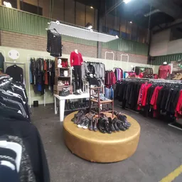 Winkelvloer met kledingrekken, een geel rond schoenenrek in het centrum en verschillende afdeling met zwarte en rode kleding