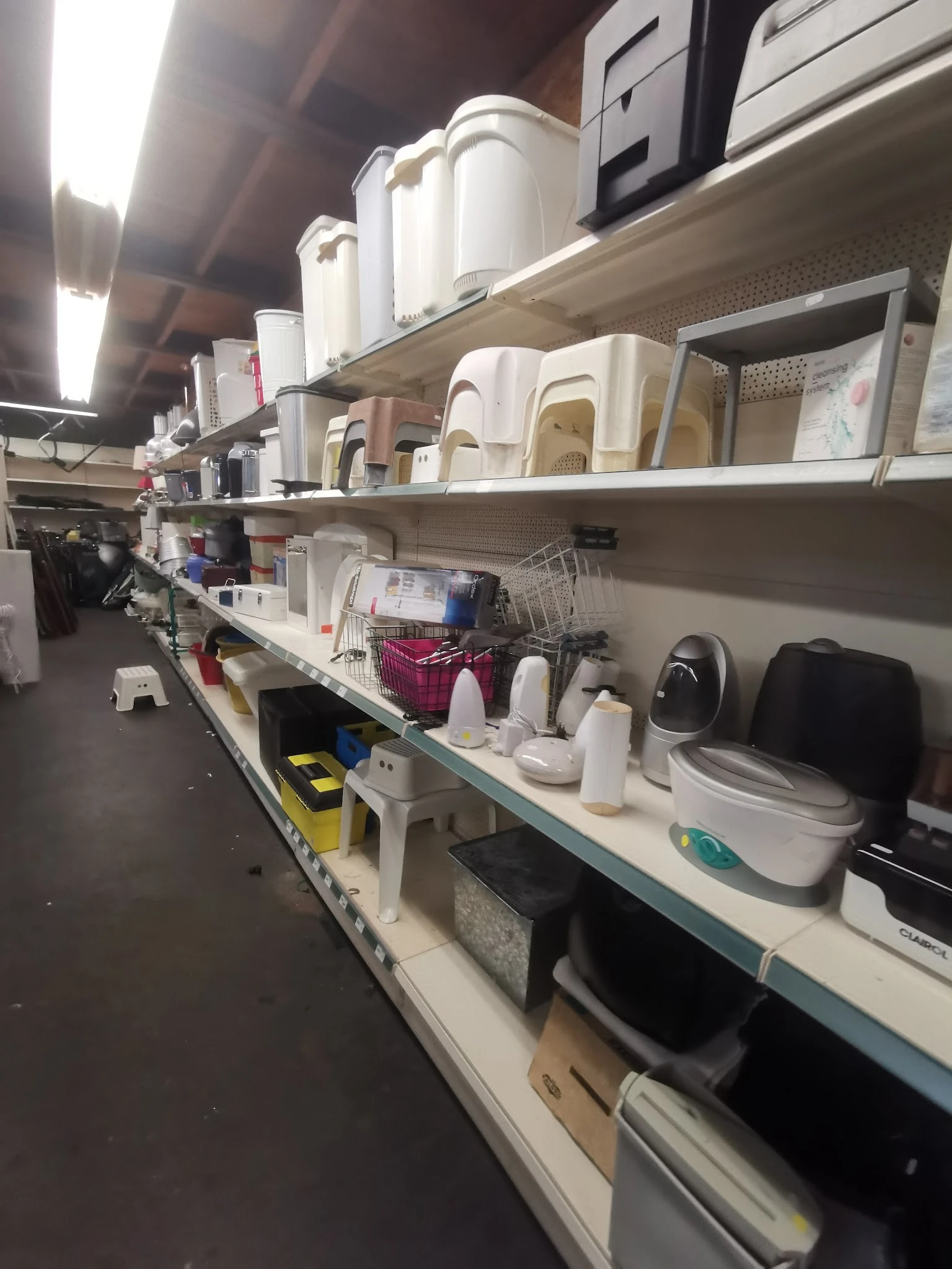 Stellingen met huishoudartikelen zoals plastic bakken, emmers en schoonmaakspullen in de kringloopwinkel