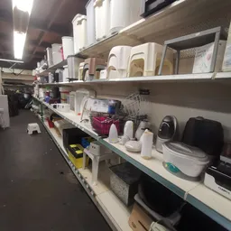 Stellingen met huishoudartikelen zoals plastic bakken, emmers en schoonmaakspullen in de kringloopwinkel