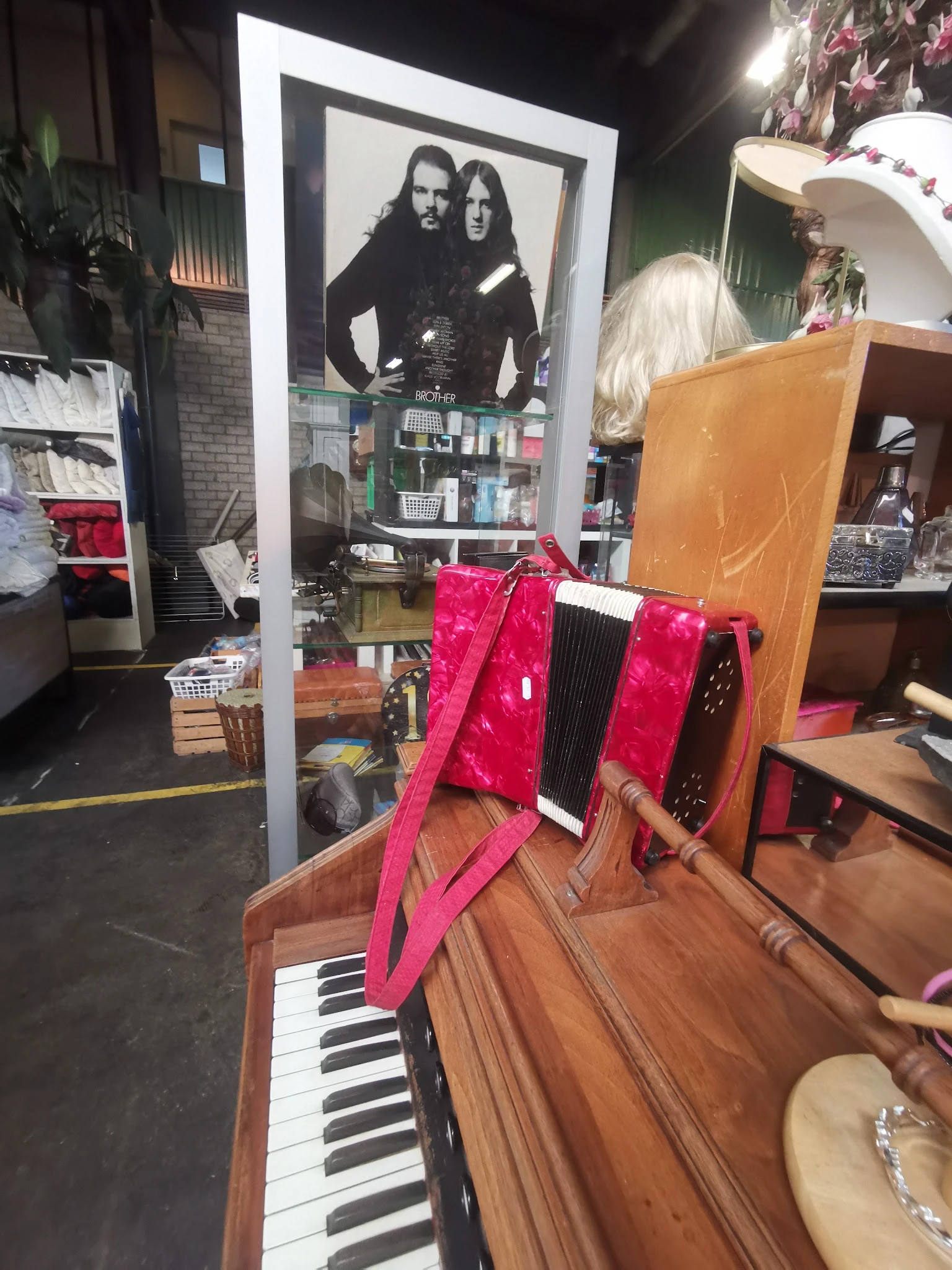 Roze handtas of reistas met zwarte details, uitgestald op houten meubel in kringloopwinkel