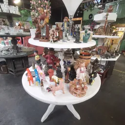 Twee witte ronde tafels vol met verzamelde beeldjes, speelgoed en decoratieve voorwerpen in verschillende stijlen en material
