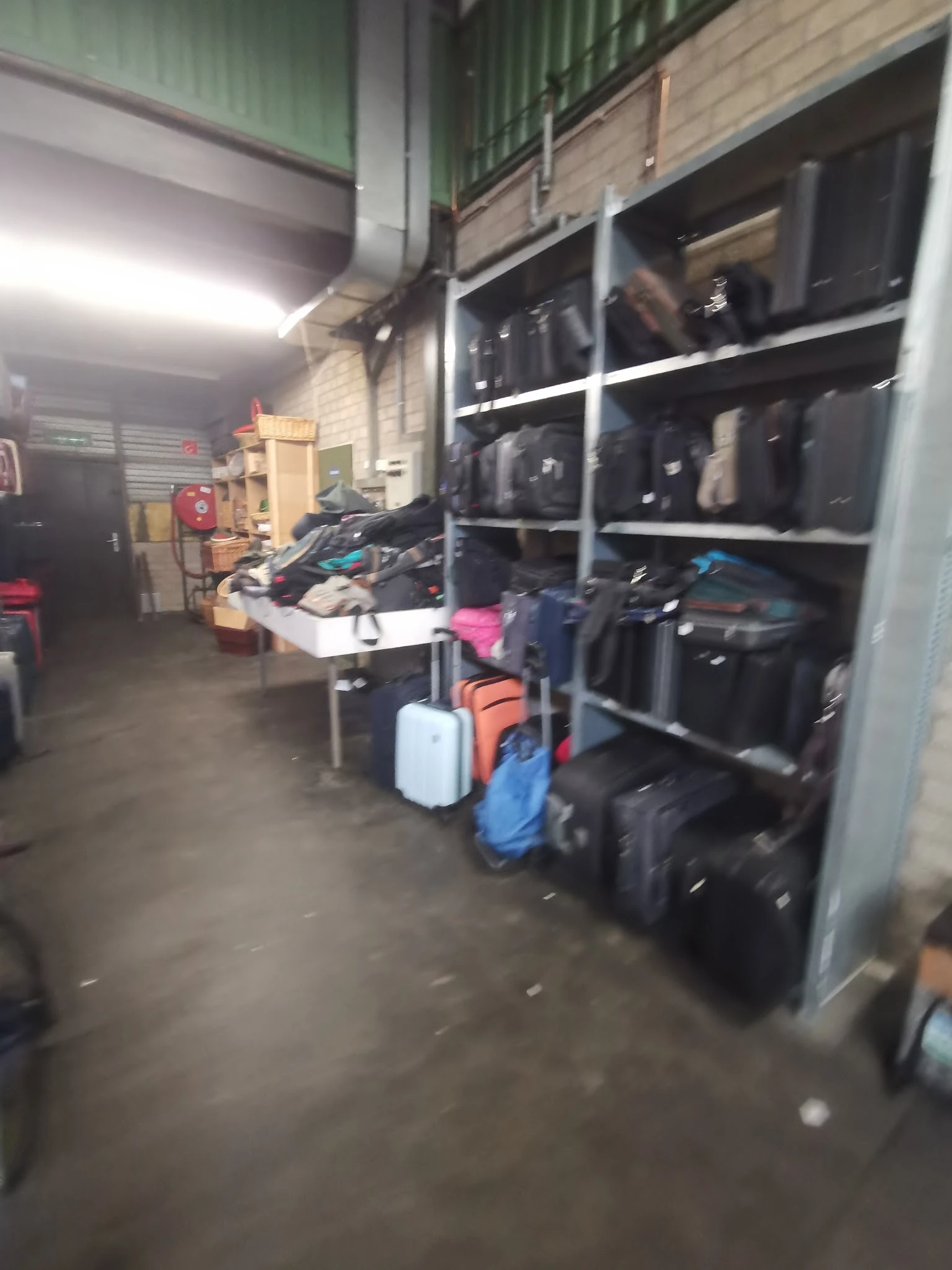 Magazijnruimte met koffers, tassen en gevulde stellingen met donkere kleding