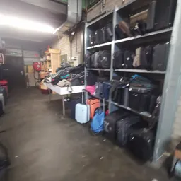 Magazijnruimte met koffers, tassen en gevulde stellingen met donkere kleding
