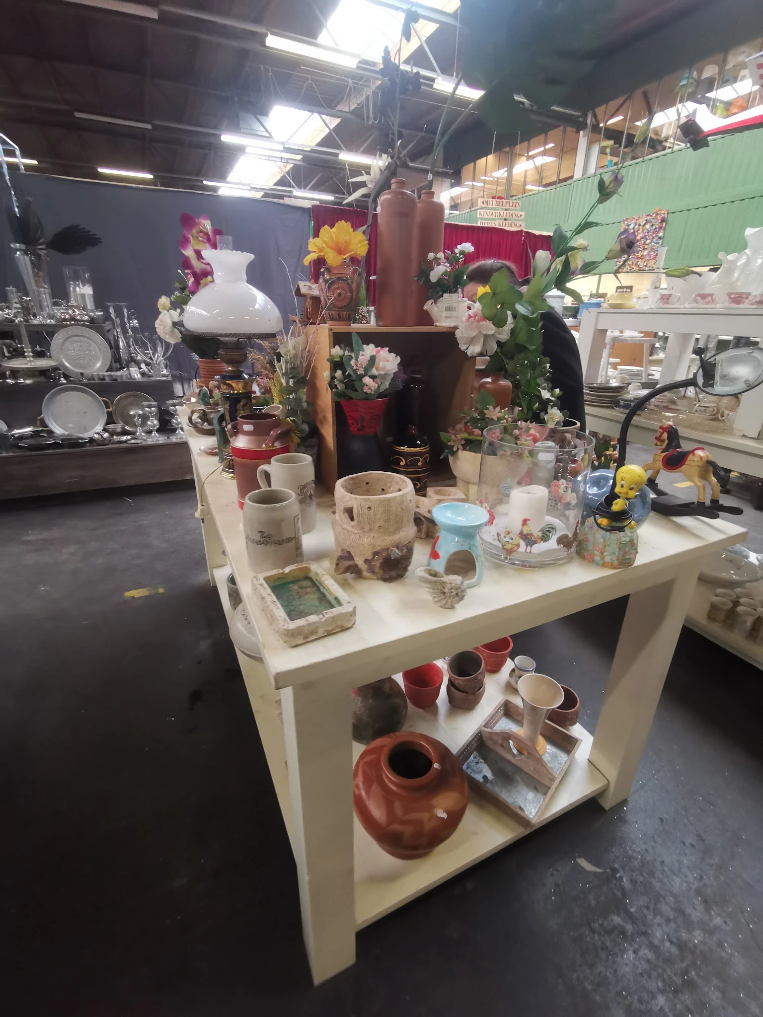 Witte toonbank met decoratieve items: vazen, bloempotten, serviesgoed en andere huishoudelijke voorwerpen