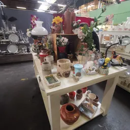 Witte toonbank met decoratieve items: vazen, bloempotten, serviesgoed en andere huishoudelijke voorwerpen