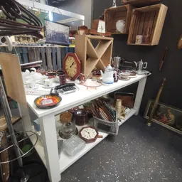Witte display tafel met huishoudelijke artikelen: klokken, servies, glazen, kandelaars en andere decoratieve items