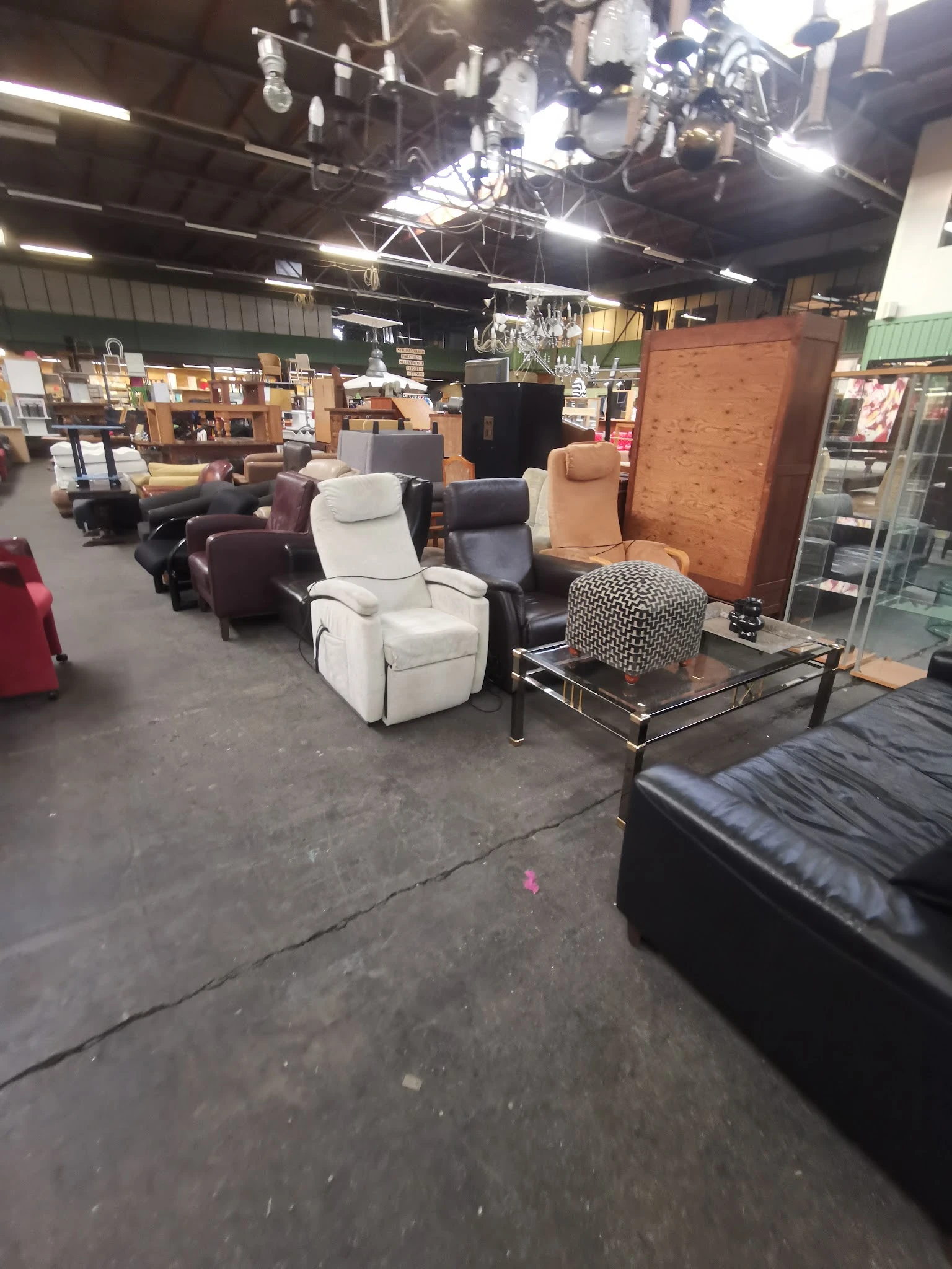 Winkelvloer met meubels uitgestald: diverse fauteuils en stoelen in wit, zwart en bruin, met zittingspuffKUSEN en een grote k