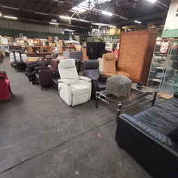 Winkelvloer met meubels uitgestald: diverse fauteuils en stoelen in wit, zwart en bruin, met zittingspuffKUSEN en een grote k