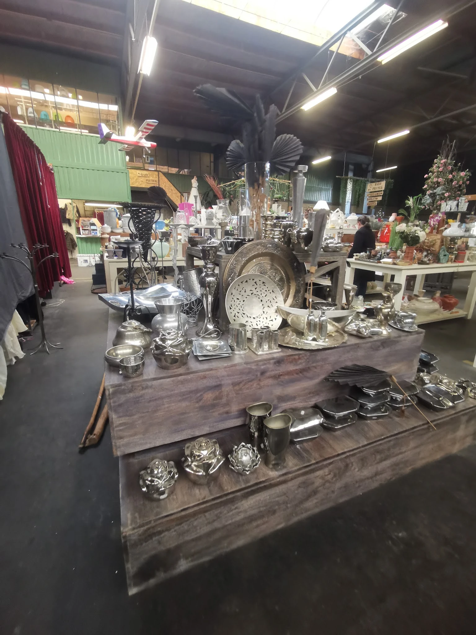 Uitgestalde zilverkleurige huishoudelijke artikelen en decoratieve items op tafels in de winkel