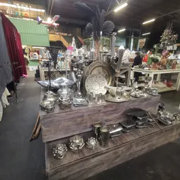Uitgestalde zilverkleurige huishoudelijke artikelen en decoratieve items op tafels in de winkel