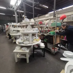Uitgestalde serviesgoed en huishoudartikelen op witte tafels in de kringloopwinkel