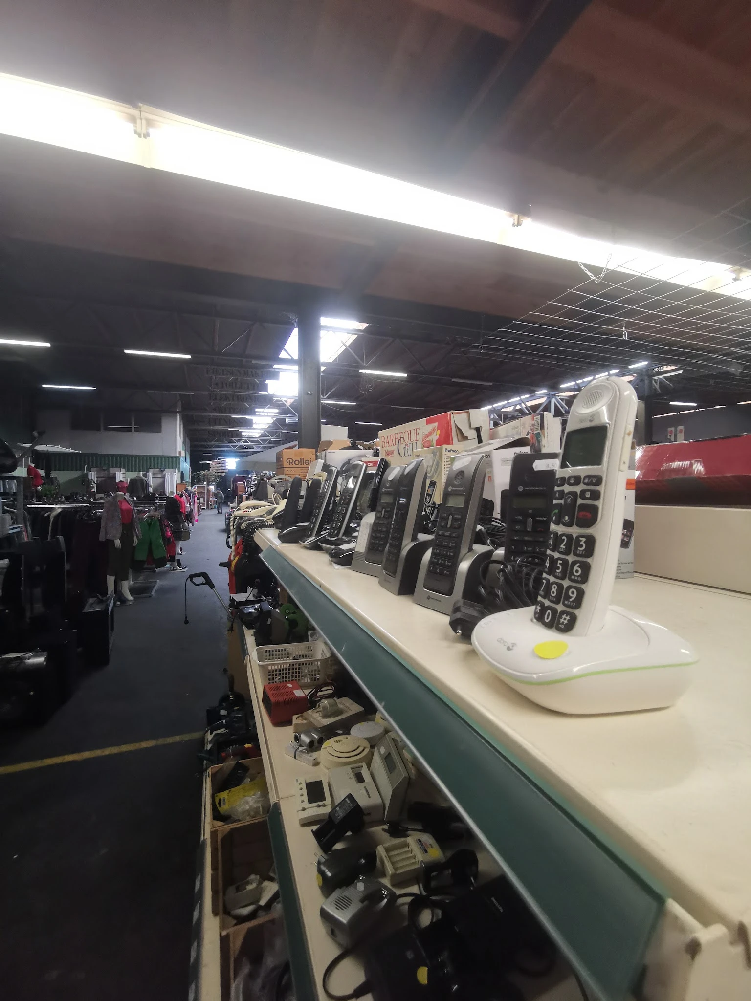 Rij van tweedehands mobiele telefoons en elektronische apparaten op een toonbank in de kringloopwinkel
