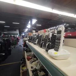 Rij van tweedehands mobiele telefoons en elektronische apparaten op een toonbank in de kringloopwinkel