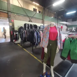 Rekken met tweedehands kleding, waaronder jasjes en broeken, met kledingpoppen die outfits presenteren
