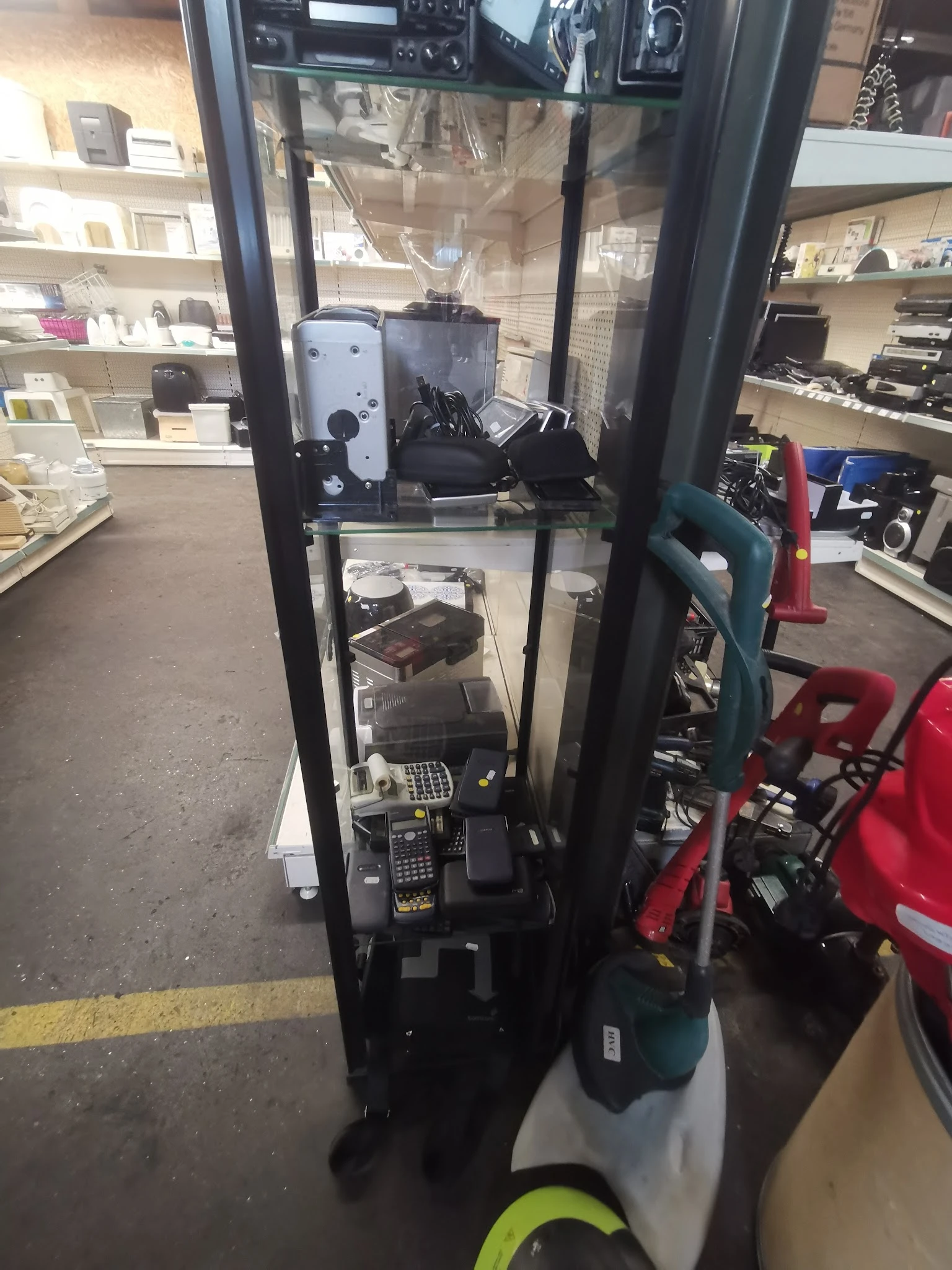 Stellingkast met tweedehands elektronische apparaten en huishoudelijke items in een kringloopwinkel