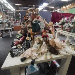 Collectie antieke poppen en poppenkleding uitgestald op een tafel in de winkel