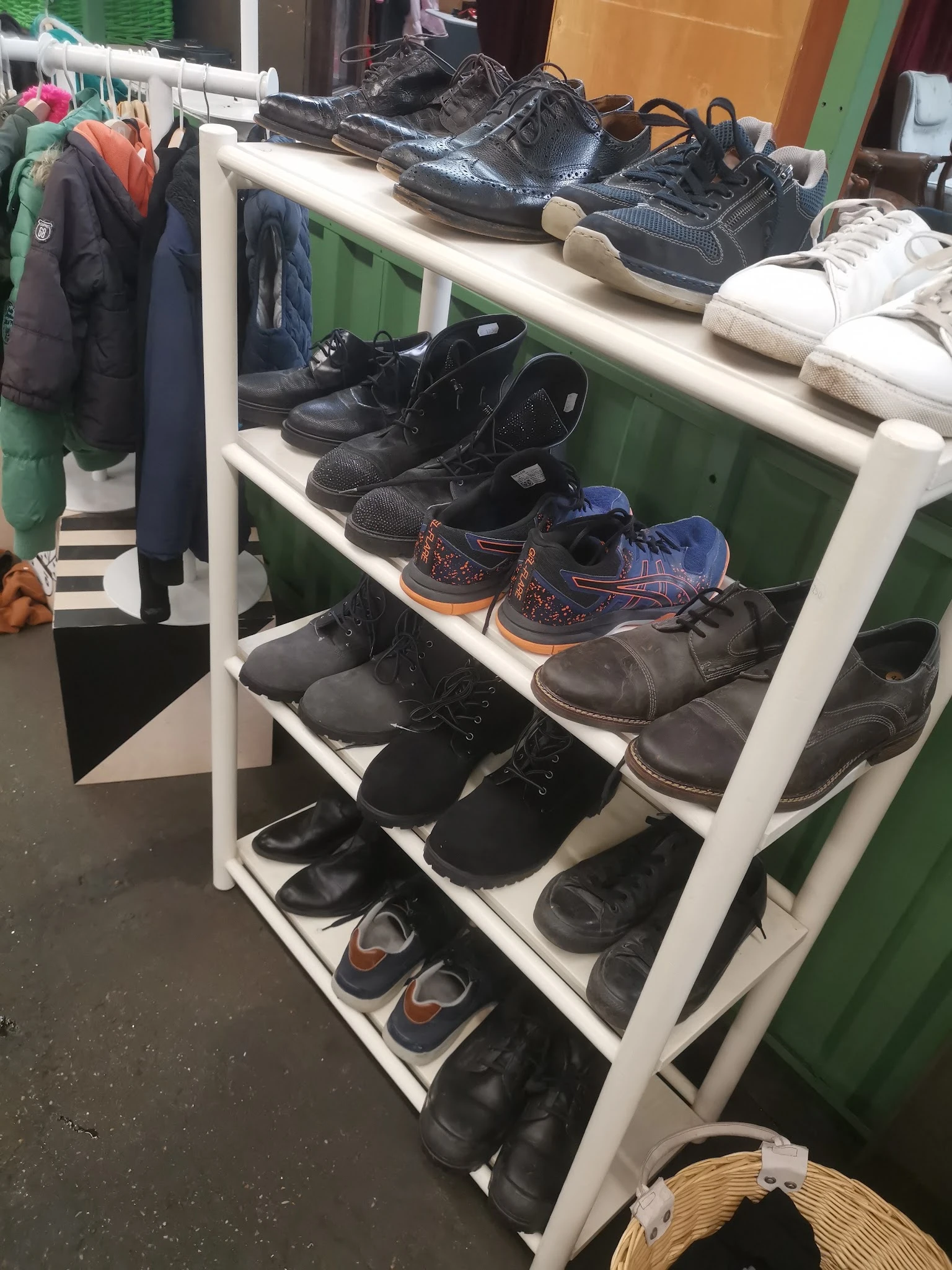 Wit metalen schoenenrek met diverse tweedehands schoenen en laarzen in verschillende kleuren