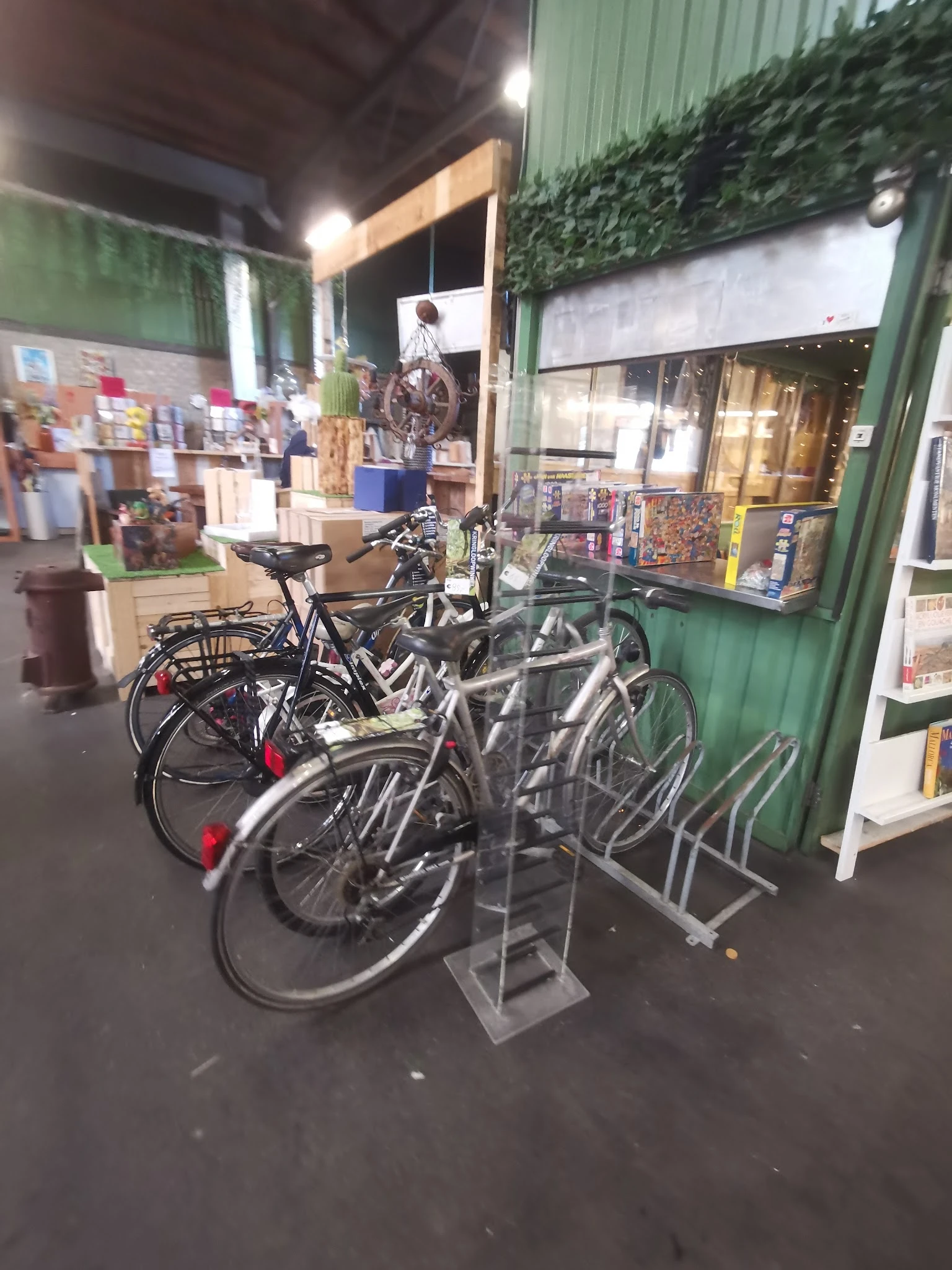 Uitgstalde tweedehandsfietsen in een rek bij de ingang van de kringloopwinkel