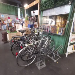 Uitgstalde tweedehandsfietsen in een rek bij de ingang van de kringloopwinkel