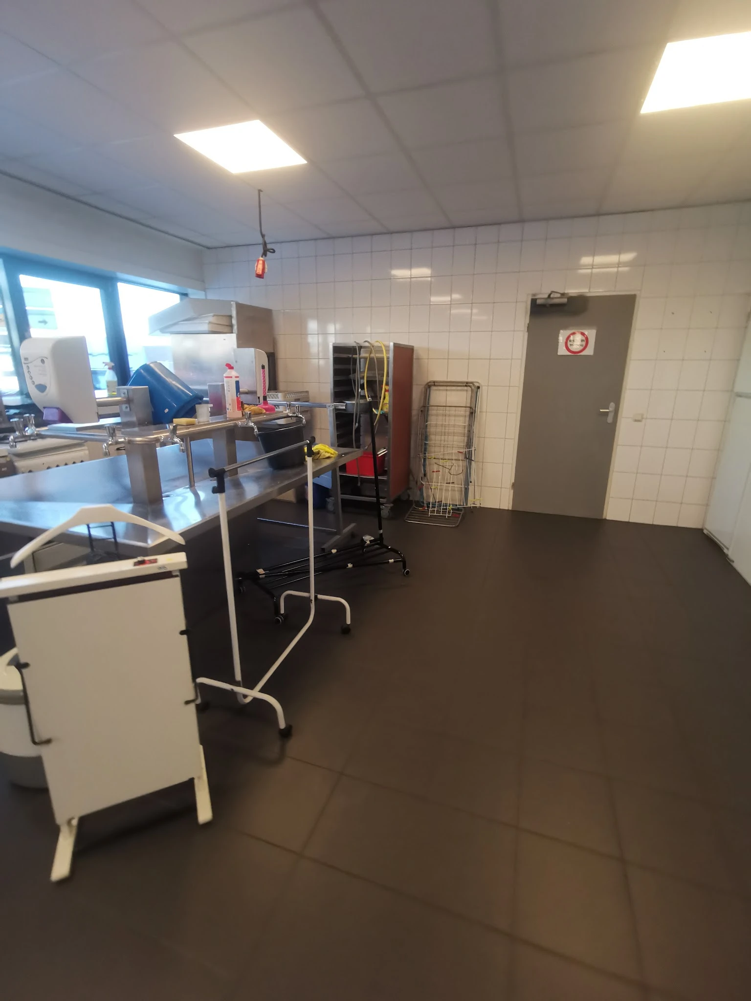 Winkelvloer van kringloopwinkel met stellingen, werktafels en diverse spullen in het magazijngedeelte