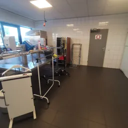 Winkelvloer van kringloopwinkel met stellingen, werktafels en diverse spullen in het magazijngedeelte